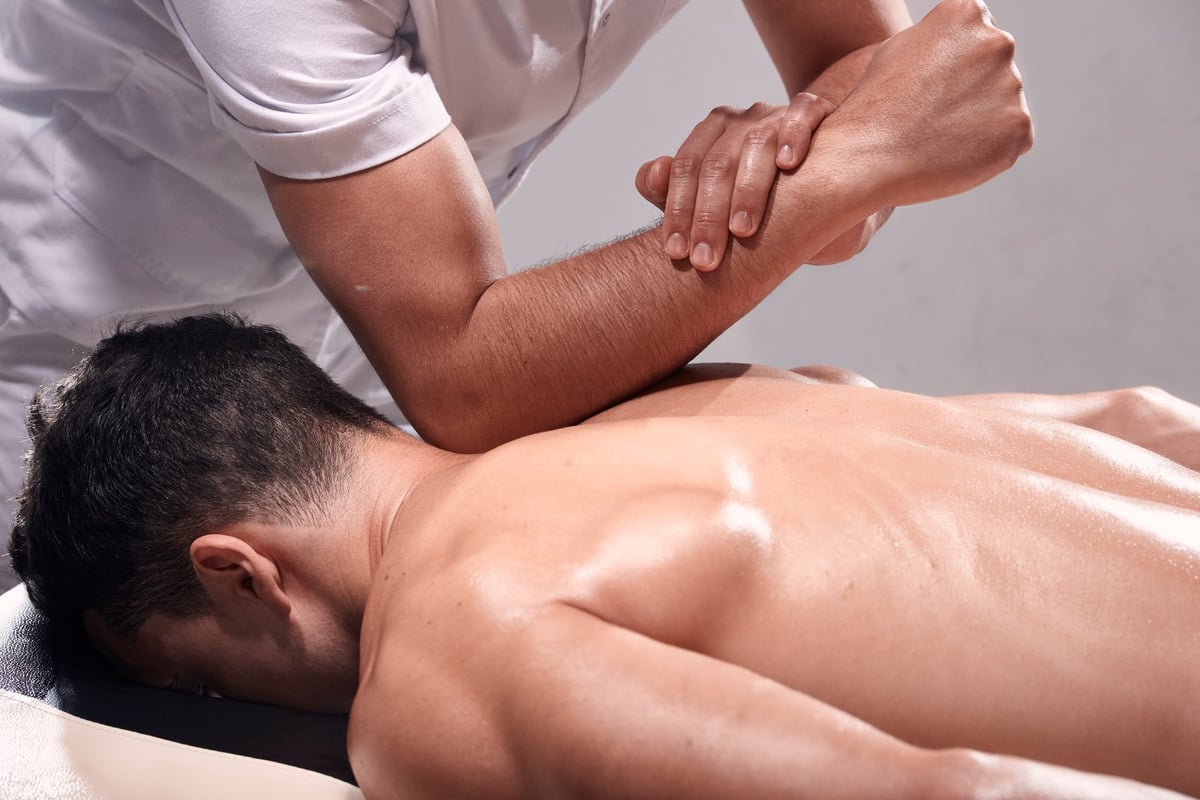 A therapist using his elbow to work deep into a client's upper back
