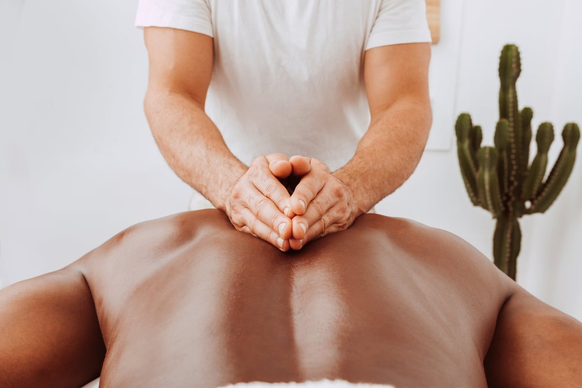 A masseur giving a gentle back massage to a client in a spa salon after sport