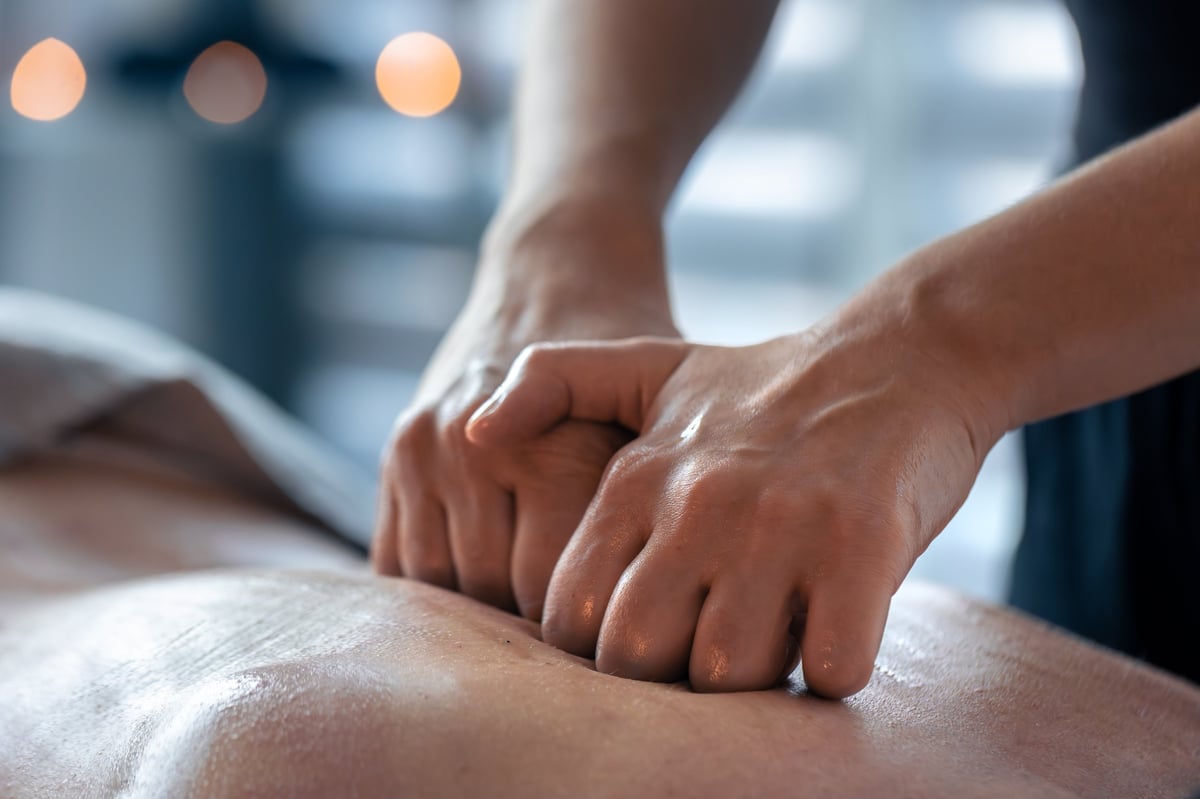 A therapist applying deep pressure across a client's back