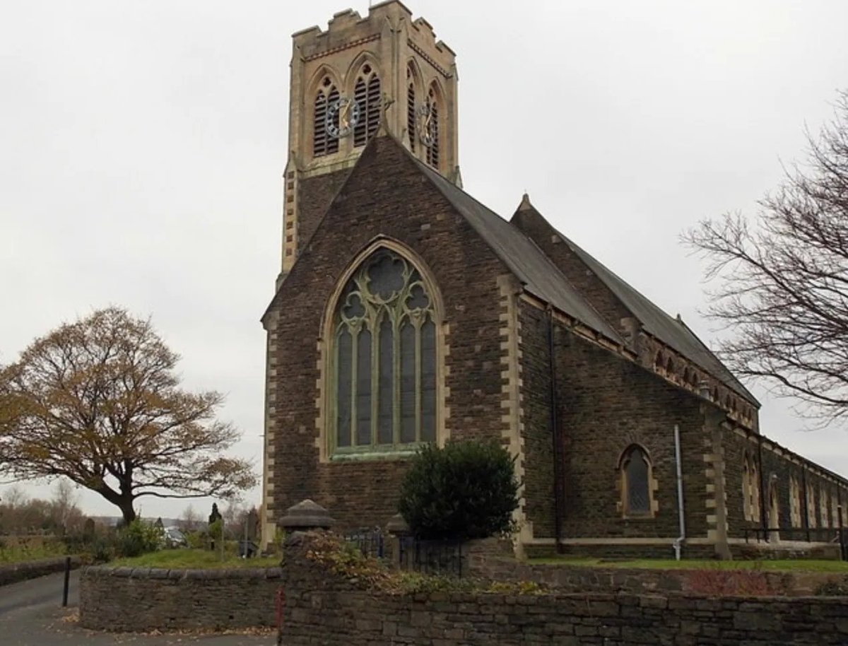 Historic stone church with crenellated tower, Gothic-style windows, and graveyard surrounded by bare trees