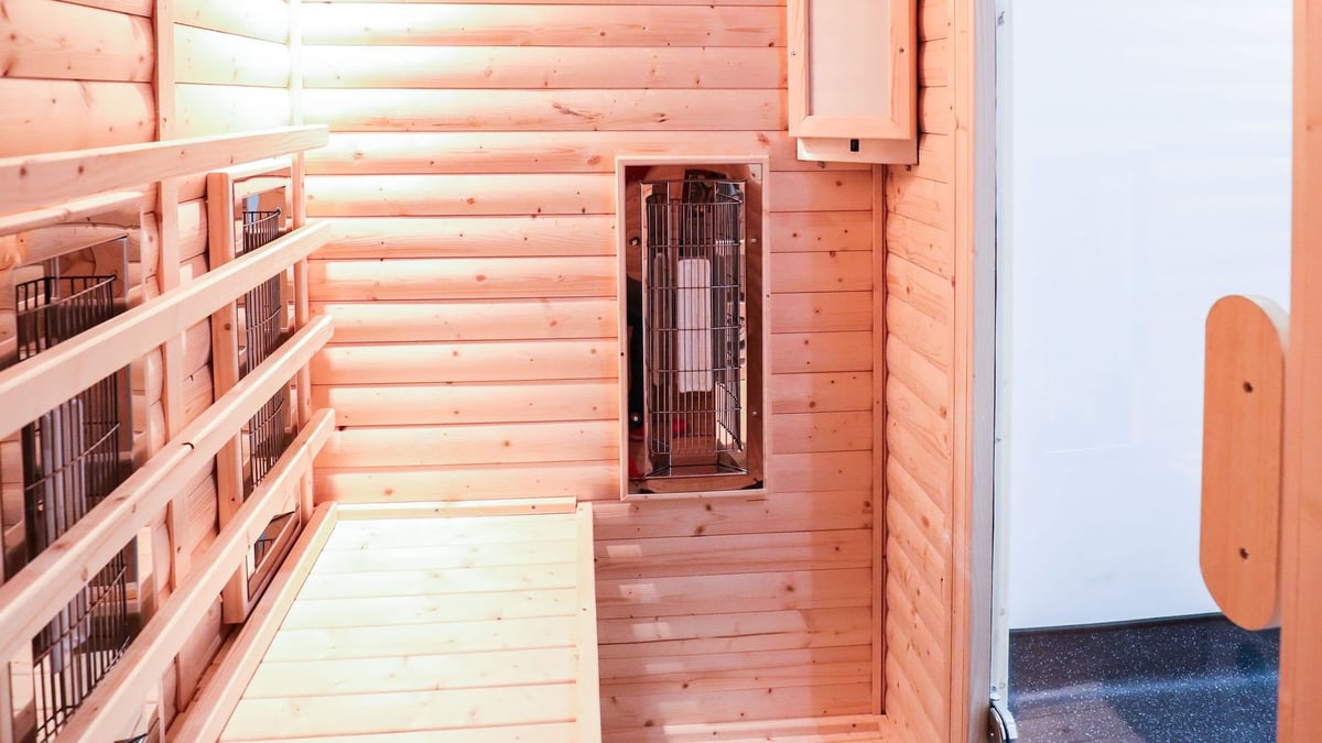 The infrared sauna at the Birchgrove treatment room, with timber panelling, a bench along one side and a heat lamp mounted on the wall