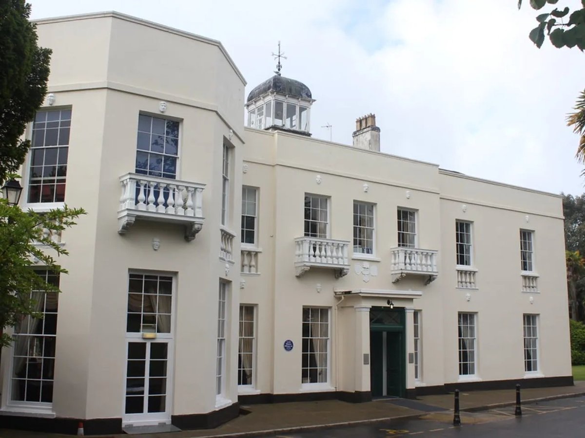 White Georgian-style building with symmetrical windows, a central domed cupola, and balustrades